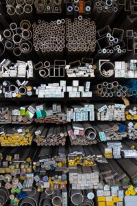 Diverse collection of stacked metallic pipes and rods in a warehouse display.