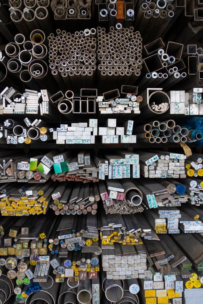 Diverse collection of stacked metallic pipes and rods in a warehouse display.