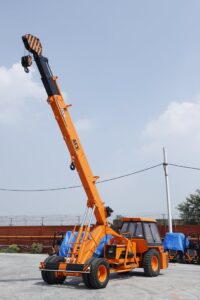 Orange ACE mobile crane in use at an outdoor construction site in Faridabad, India.